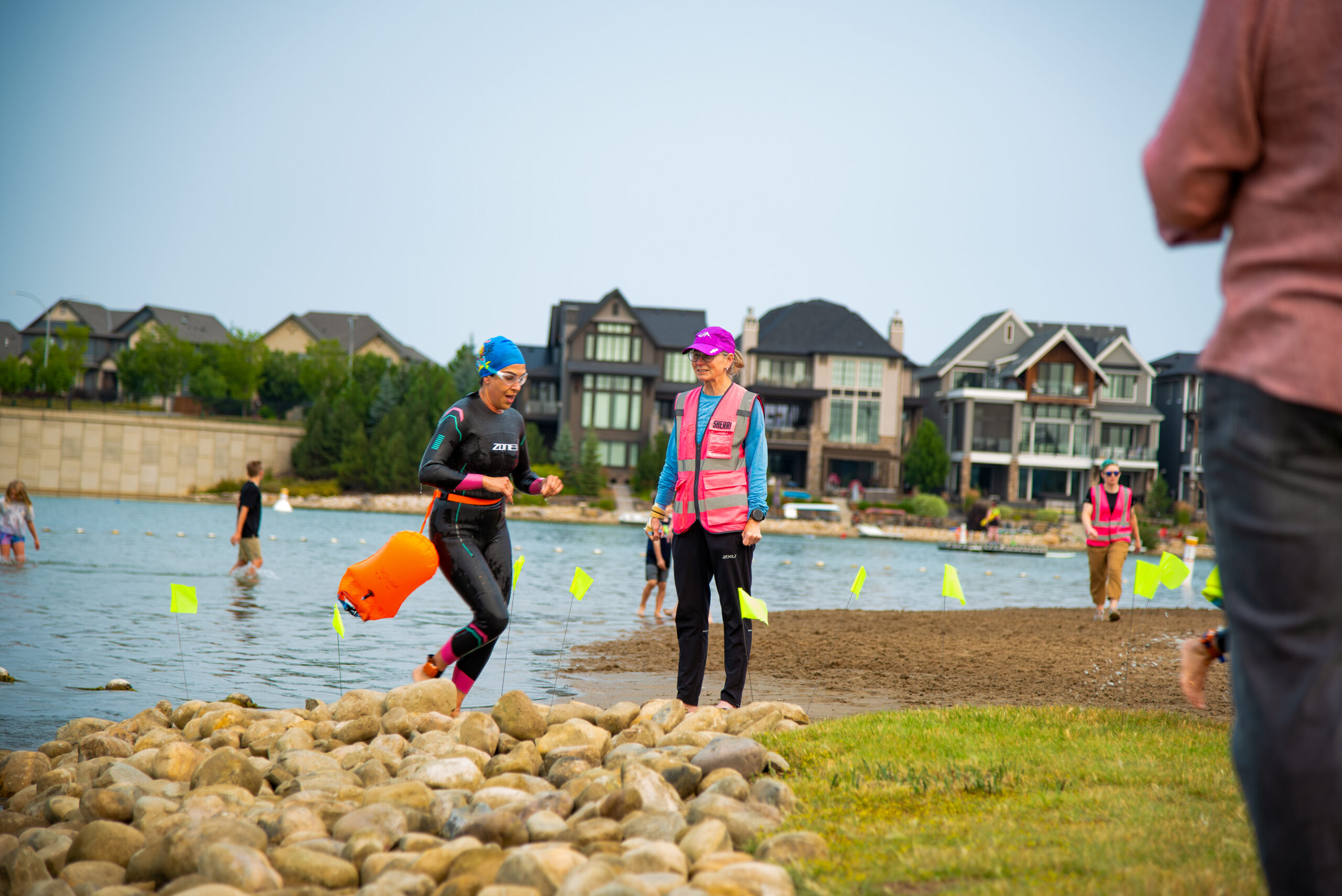 Swimmers mid-course during the Beach 2 Beach open water swim, with buoys and safety kayaks visible